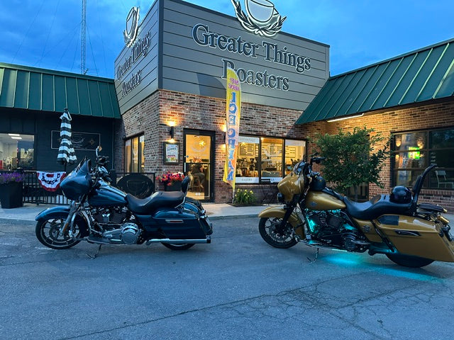 Two motorcycles parked outside Greater Things Roasters at dusk